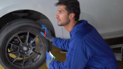 Portrait of latin auto mechanic man using clipboard checking tire and wheel to change in garage cars service . hispanic technician repairing vehicle at garage . maintenance car repair service