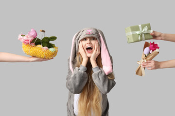 Beautiful young shocked woman in bunny costume and hands holding bouquet of flowers, gift box with...