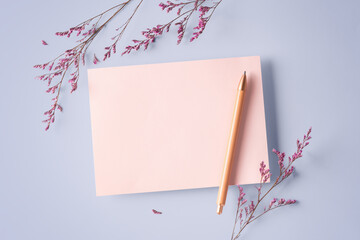 Pink card with pen and pink flower on pastel purple background