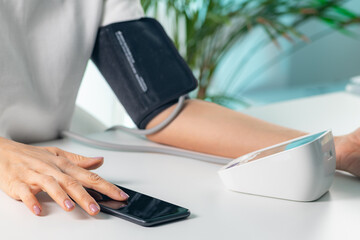 Modern approach to healthcare as data is entered into a smartphone while measuring blood pressure