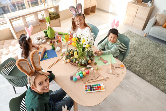 Little children in bunny ears making Easter crafts on table at home