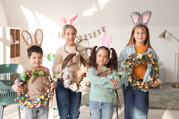 Little children in bunny ears with Easter wreaths at home