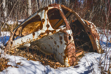 weathered  car body dumped in forest nature in winter season