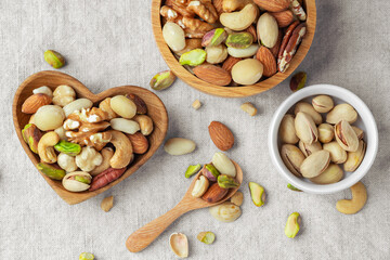 Various nuts in wood bowls with spoon on linen tablecloth