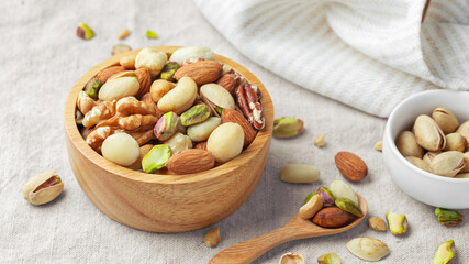 Nuts mixed in wooden bowl with spoon on linen tablecloth