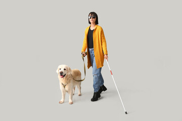 Blind woman with guide dog on grey background