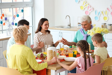 Happy family praying before Easter dinner in kitchen