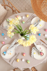 Festive Easter table setting with vase of flowers, cutlery, napkins and painted eggs