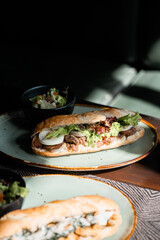 Two sandwich with lettuce, tomato, cheese, meat, and eggs on green plate