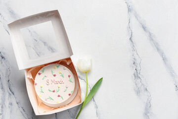 Box with sweet bento cake and beautiful tulip on white background. International Women's Day