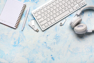 Notebook, computer keyboard and headphones on blue grunge background