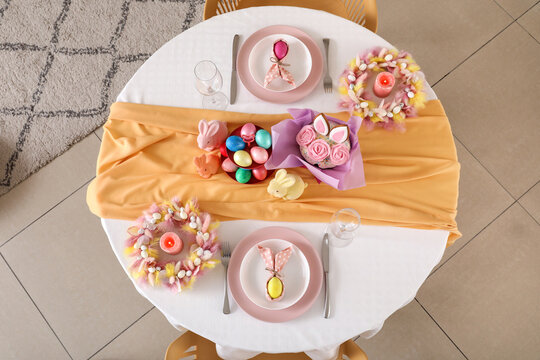 Festive table serving with painted eggs and bunnies for Easter celebration, top view
