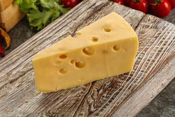 Swiss Maasdam cheese triangle over board