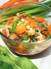Asian home made food, sauteed vegetable carrot, beans, and mushroom, with cutting onion and garlic.