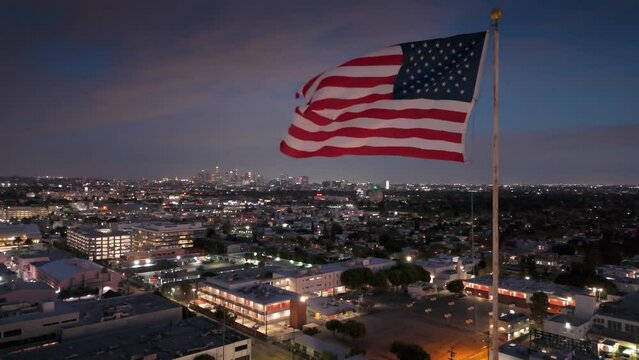 USA flag waving over Los Angeles cityscape at night.  American dream and  freedom concept.