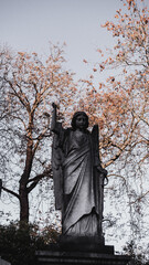 Amidst the cemetery's hallowed grounds, an ancient angelic figure stands as a sentinel, embodying...