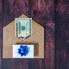A paper envelope with 20 dollars in it on a dark brown wooden background. Flatley with a gift	
