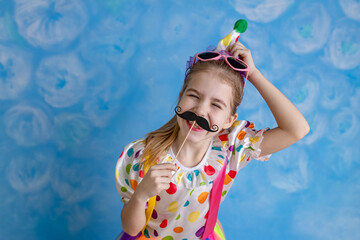 Funny kid clown playing against a bright wall. 1 April Fool's day concept, birthday concept