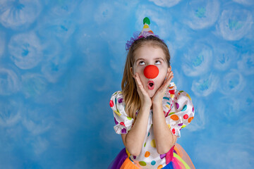 Funny kid clown playing against a bright wall. 1 April Fool's day concept, birthday concept