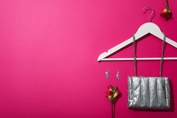 Female accessories, hanger and flowers on pink background, space for text