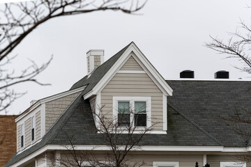 Dormer windows on the sloped shingle roof of a newly built family house on a winter day in Brighton, MA, USA - obrazy, fototapety, plakaty
