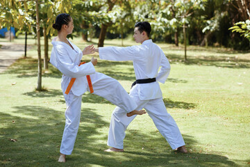 Girl with orange belt defending when fighting with black belt taekwondo athlete