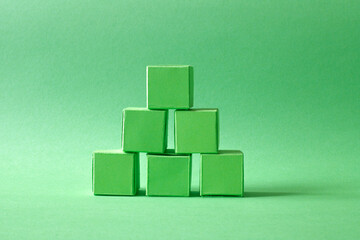 Green Cubes Organized in a Pyramid Formation on Uniform Teal Green Background Representing Eco-Friendly Development