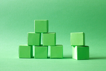 Green Cubes Organized in a Pyramid Formation on Uniform Teal Green Background Representing Eco-Friendly Development