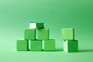 Green Cubes Organized in a Pyramid Formation on Uniform Teal Green Background Representing Eco-Friendly Development
