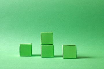 Green Cubes Organized in a Pyramid Formation on Uniform Teal Green Background Representing Eco-Friendly Development