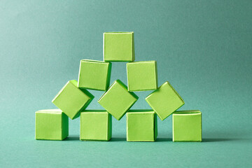 Green Cubes Organized in a Pyramid Formation on Uniform Teal Green Background Representing Eco-Friendly Development