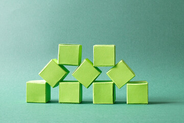 Green Cubes Organized in a Pyramid Formation on Uniform Teal Green Background Representing Eco-Friendly Development