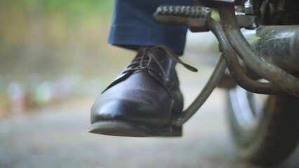 Closeup shot of a man trying to kick start an old motorbike