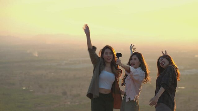 Group of Asian young women having fun and enjoying a summer vacation vlogging from the mountain in nature during sunset. Females Lifestyle, blogger travel