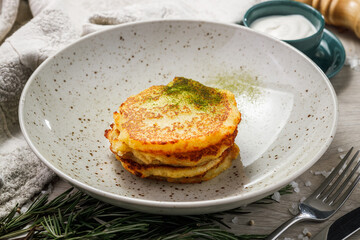 Pancakes with sour cream and herbs on a plate. Selective focus.