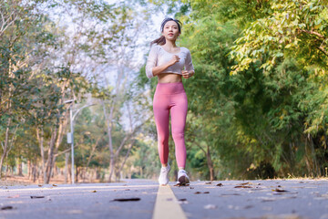 Young Asian woman jogging in the morning at a public park on a bright sunny day.