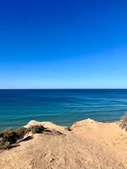 Fototapeta na wymiar Sandstone rocky coast, blue ocean horizon, clear sky, ocean bay