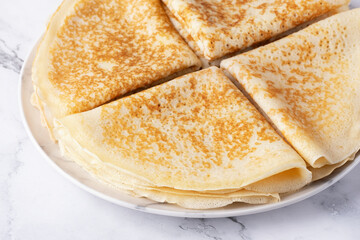 A stack of thin pancakes on a light marble table