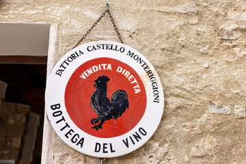 Fototapeta premium Black rooster symbol of good wine in Tuscany hanging on the wall of a house in Monteriggioni medieval walled town near Siena. Italy