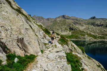 Fototapeta na wymiar hiker on Bachimaña reservoir, Ibones azules and Bachimaña alto route, Huesca province, Spain
