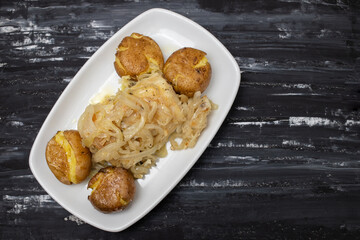 Tasty pieces of baked potatoes and salt and oil on plate