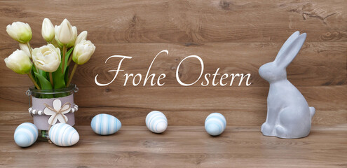 Frohe Ostern: Ostereier und Osterdekoration vor einer Holzwand mit dem Text Frohe Ostern.