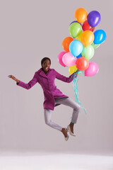 Fototapeta na wymiar Balloon, jump and portrait of happy black woman in studio for birthday, celebration and present. Fashion, excited and isolated person with inflatable for party, gift and surprise on gray background