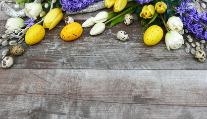 Farbenfrohe Osterdekoration mit Blumen auf schäbigen Holzbrett mit Platz für Text.