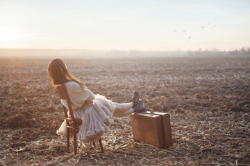 traveler woman rests sitting on a chair in the middle of nature, concept of freedom and well-being - 748584236