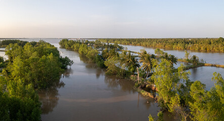 Aerial evening panoramic view of a side arm of the Ham Luong River in Vietnam's Mekong Delta, a unique landscape dominated by water, islands and tropical rainforest