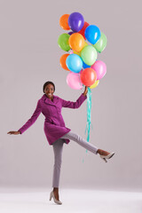 Balloon, excited and portrait of black woman in studio for birthday, celebration and present. Happy, fashion and isolated person smile with inflatables for party, gift and surprise on gray background