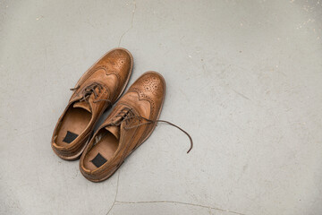 Vintage men's leather shoes with laces on a gray concrete background.