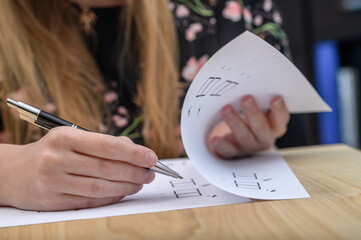 Kobieta siedzi przy stole wypelnia formularze, przeklada kartki i zaznacza pola 