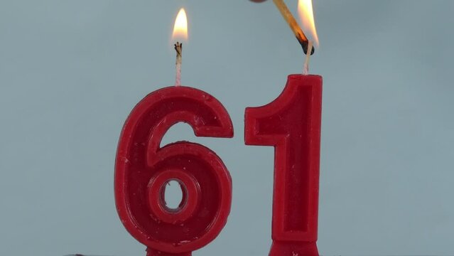 close up on a red number sixty one birthday candle on a white background.
